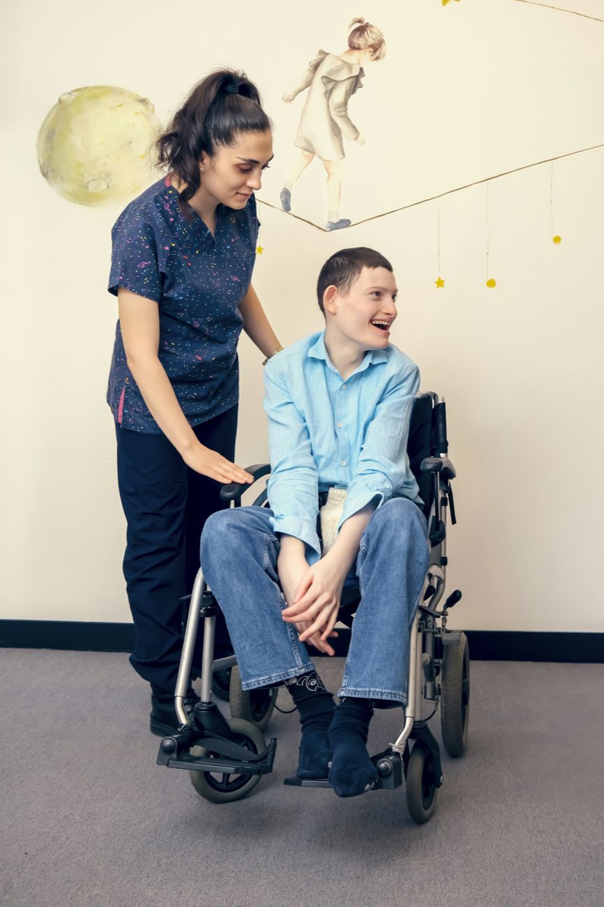 Young man in a wheelchair with a helper