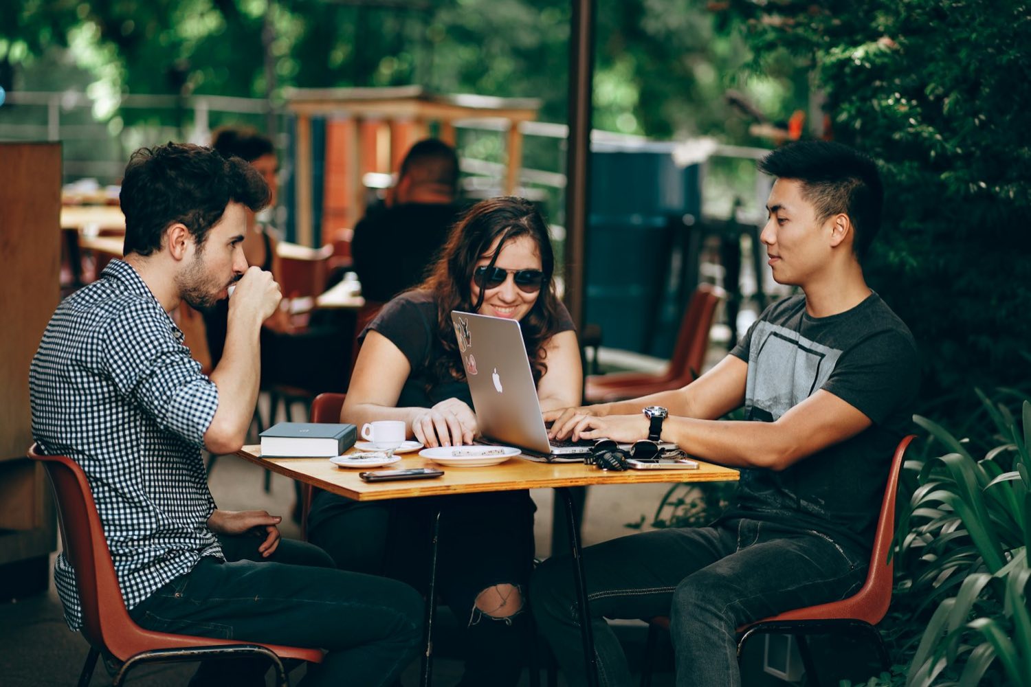 Three students at a cafe table with a laptop