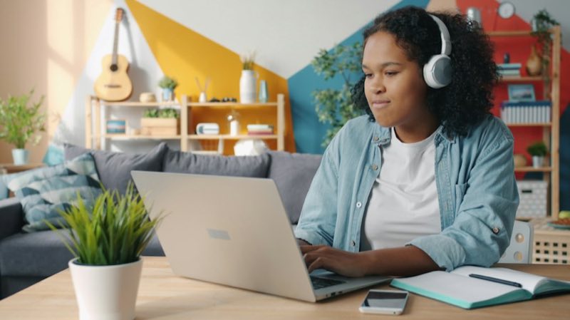 Student in headphones working on a laptop