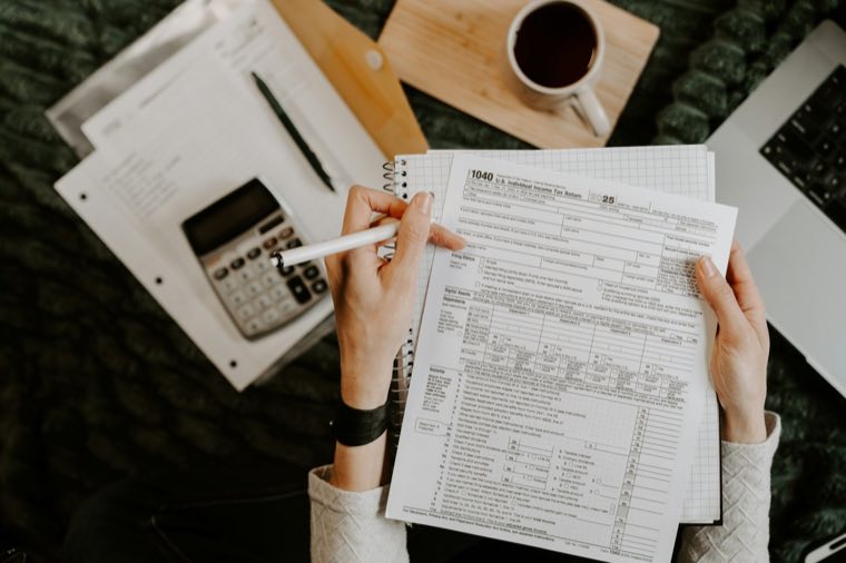 Hands holding tax forms beside a calculator